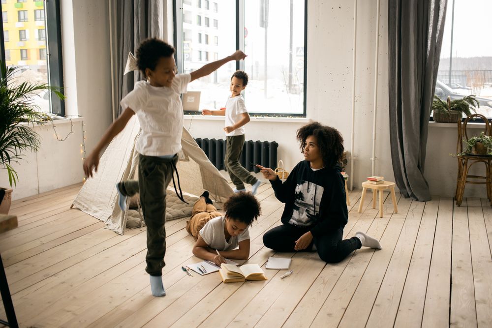 Black educator with a diverse group of children playing together in a bright room