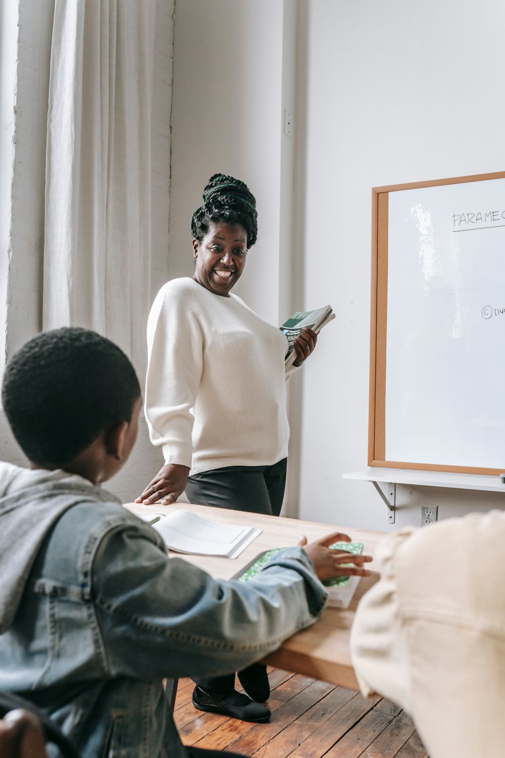 Black teacher smiling while guiding children through a classroom lesson