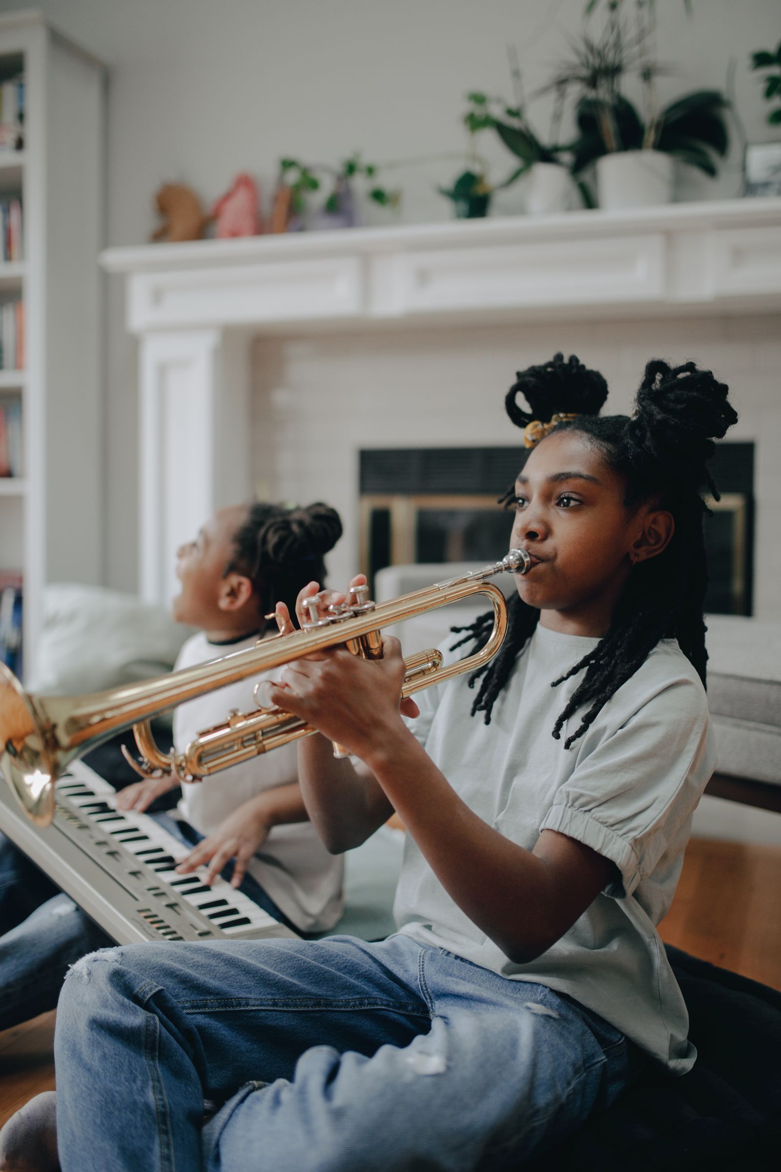 Two girls exploring music together on keyboard and trumpet